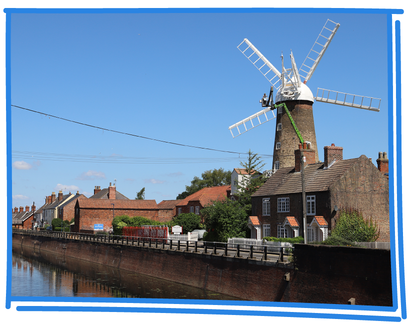 Windmill on sunny day with river in foreground